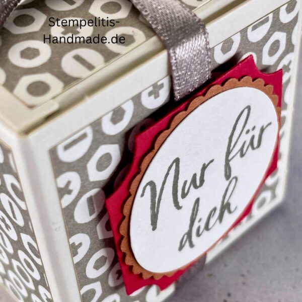 handdekorierte Geschenkschachtel mit Aufschrift „Nur für dich“, Geschenkschachtel mit grauem Muster und rotem Etikett, kleine Geschenkbox mit Satinband, Vorderansicht der Schachtel „Nur für dich“, offene Geschenkbox mit Inhalt, Detailaufnahme Schriftzug „Nur für dich“, stilvolle Geschenkverpackung mit Band